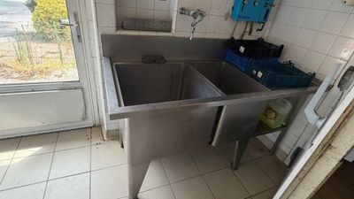 a sink in the corner of a kitchen with a door open