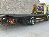 a tow truck with a flat bed parked in front of a building
