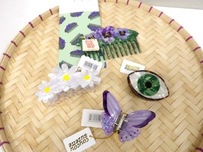 des accessoires pour cheveux violets et blancs posés sur un plateau en bambou posé sur une table