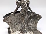 a silver statue of a woman sitting on top of a chair