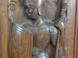 carved wood panel of a knight holding a sword and shield