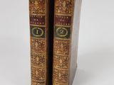 two old books are sitting side by side on a white surface