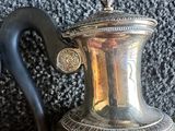une cafetière en argent posée par terre à côté d'une poignée noire