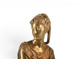 a gold statue of a woman sitting on a white surface