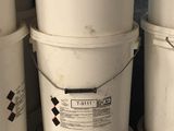 several white buckets are stacked on top of each other in a garage