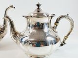 two silver teapots sitting next to each other on a table
