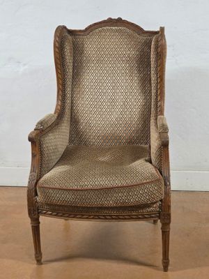 an old fashioned chair with a brown upholstered seat and a beige upholstered back