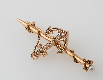 a close up of a gold and pearl broochle with a dagger