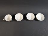 three white coffee cups sitting on top of a black table