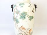 un vase blanc avec un tableau posé sur une table