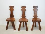 three wooden chairs sitting next to each other against a white wall