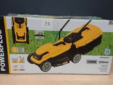 une tondeuse à gazon Powerplus jaune et noire, dans son carton, posée sur une table