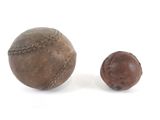 deux vieilles balles de baseball posées l'une à côté de l'autre sur une surface blanche