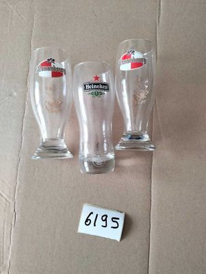 three beer glasses sitting on top of a cardboard box next to a price tag
