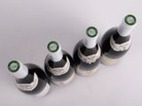 four bottles of wine are lined up on a white surface