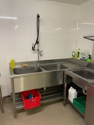une cuisine équipée d'un évier, d'un plan de travail et d'une poubelle