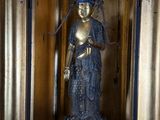 une statue représentant une femme tenant une fleur dans une pièce