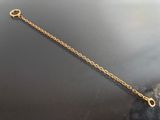 gold plated chain bracelet with a heart charm on a black surface
