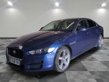 the blue jaguar car is parked in a large room with checkered flooring