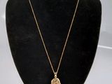 un collier en or avec une pièce de monnaie sur le cou d'un mannequin
