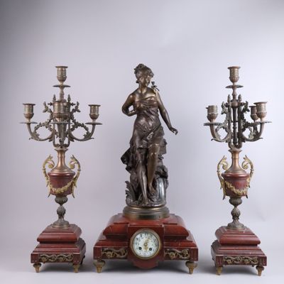 une statue représentant une femme tenant une horloge, à côté de trois chandeliers