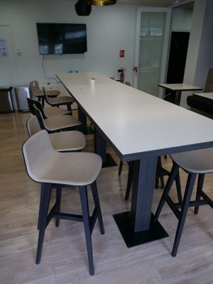 une longue table avec quatre tabourets et une télévision accrochée au mur