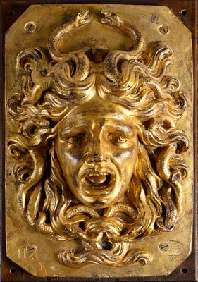 a close up of a gold plaque with a face on it