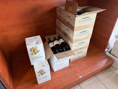 Plusieurs cartons de vin sont empilés sur une étagère dans une cuisine