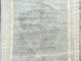 un tapis gris bordé de blanc posé sur un parquet