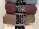 four folded blankets are stacked on top of each other