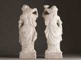 pair of white marble statues of a woman and a man holding a vase