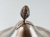 a silver plate with a lid that has a flower on it