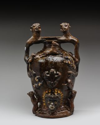 un vase marron surmonté de deux oiseaux