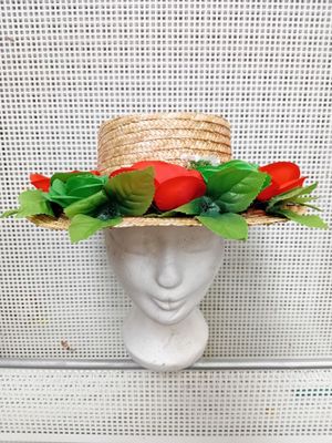 un chapeau de paille orné de roses rouges et de feuilles vertes sur la tête