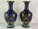 two vases sitting on a table with a white wall in the background