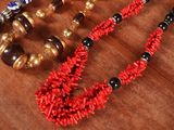 many different necklaces and bracelets on a wooden table