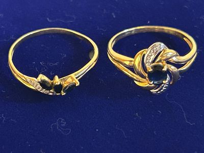 two gold rings with diamonds on them sitting on a blue surface