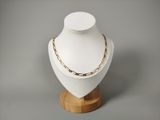 collier à chaîne en or posé sur un présentoir à mannequin, sur fond gris