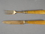 two forks and a knife on a table with a gray surface