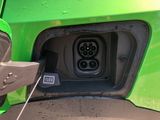 a close up of a green car with an electric plug