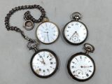 Trois montres de poche anciennes sont posées sur une table, à côté d'une chaîne