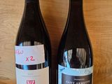 two bottles of wine sitting on a shelf next to each other