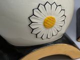 a white vase with a yellow flower on top of it