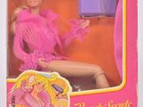 La poupée Barbie se trouve dans une boîte rose avec un sac à main violet.