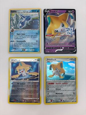 quatre cartes Pokémon différentes posées sur une surface blanche : l'une représente un chat, l'autre un chien
