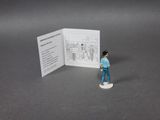 a small figurine of a man standing in front of a book