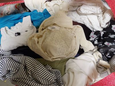 une valise pleine de vêtements et un chapeau posé par terre