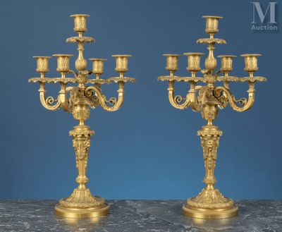 une paire de candélabres anciens en laiton posés sur une table en marbre