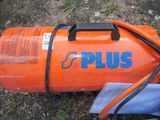 an orange gas tank sitting on the ground with a hose attached to it