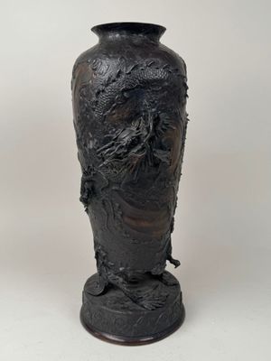 un vase noir orné d'un visage sur un fond blanc